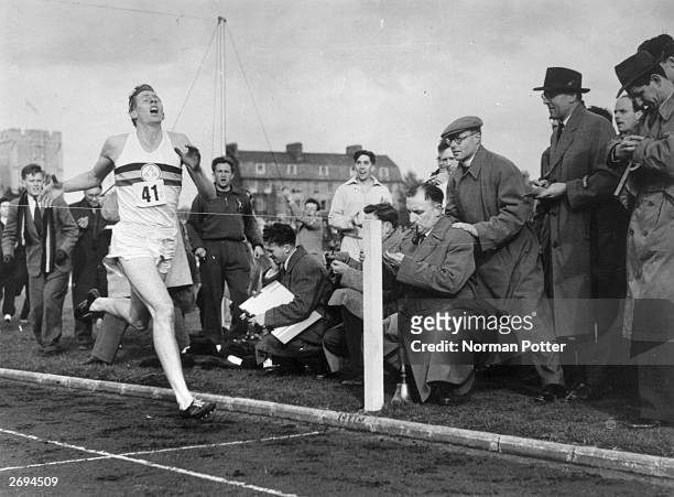 Roger Bannister about to cross the tape at the end of his record breaking mile run at Iffley Road, Oxford. He was the first person to run the mile in...