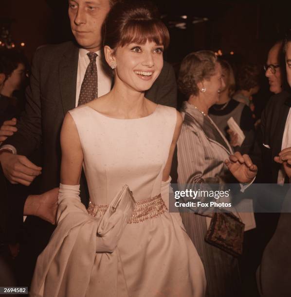 Belgian-born actress Audrey Hepburn wearing a white satin evening gown and long gloves.