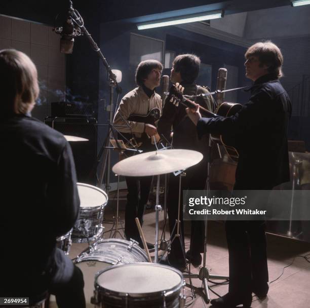 The Beatles rehearse; from left to right, Ringo Starr with his back to the camera, George Harrison at the microphone with Paul McCartney and John...