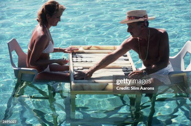 Carmen Alvarez enjoying a game of backgammon with Frank 'Brandy' Brandstetter in a swimming pool at Acapulco.