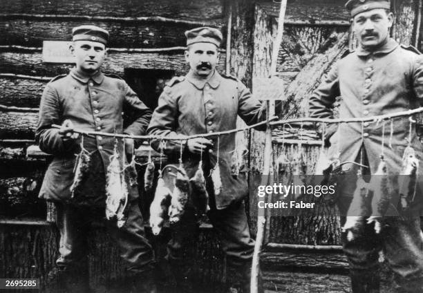 Three German soldiers display rats killed in their trench the previous night.