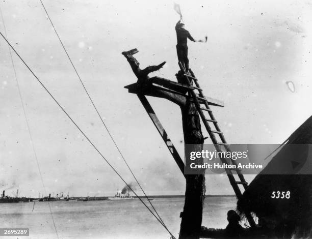 German sailor signals by semaphore for ships landing at Osel, Russia.