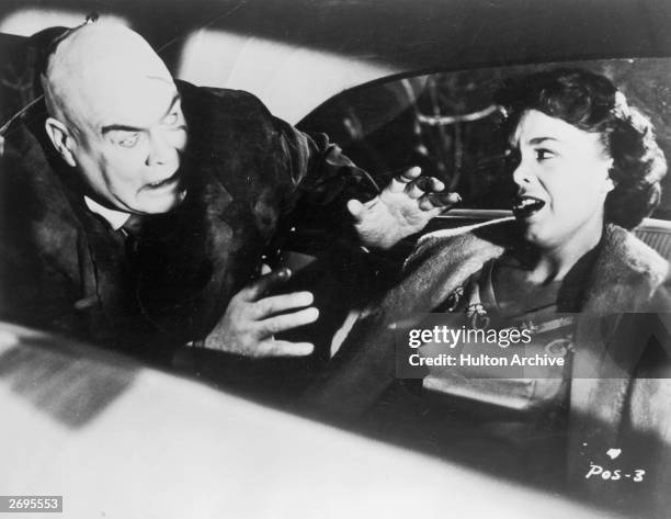 Swedish-born actor Tor Johnson attacks actor Mona McKinnon in the back seat of an automobile in a still from director Edward D. Wood Jr.'s film 'Plan...