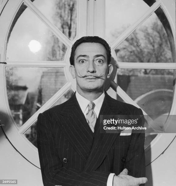 Portrait of Spanish surrealist artist Salvador Dali . He is wearing a pinstriped suit and his trademark mustache.