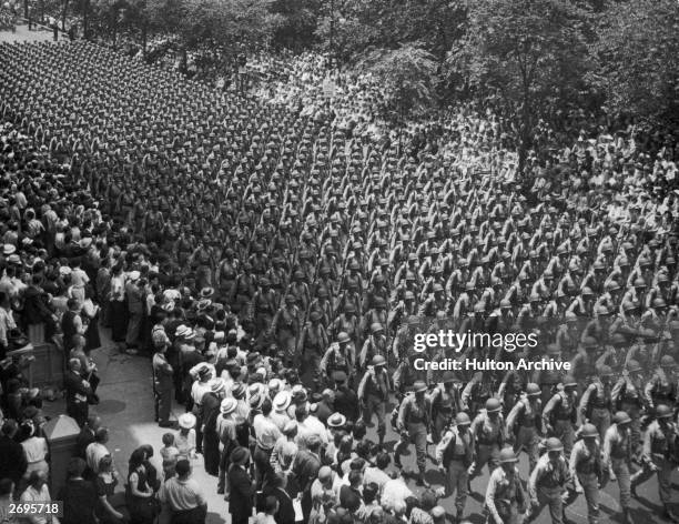 Soldiers in uniform march in rows down Fifth Avenue during a World War II victory parade in Manhattan, New York City.