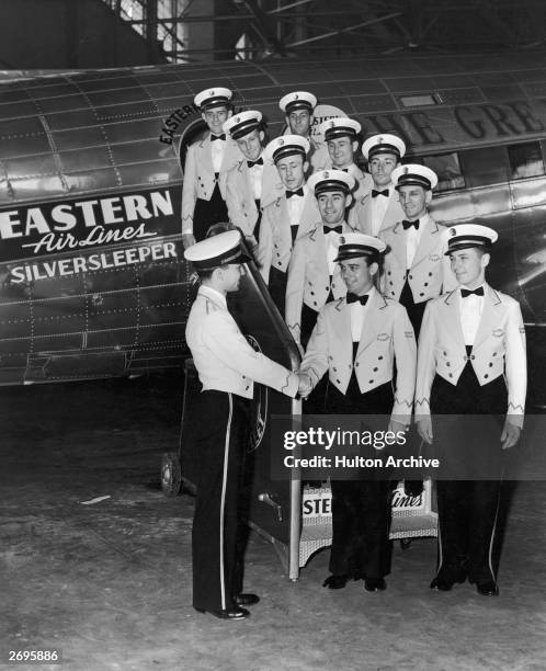 The all-male flight crew of an Eastern Airlines 'Silversleeper' airplane poses on the boarding stairwell of the plane, waiting to shake hands with a...