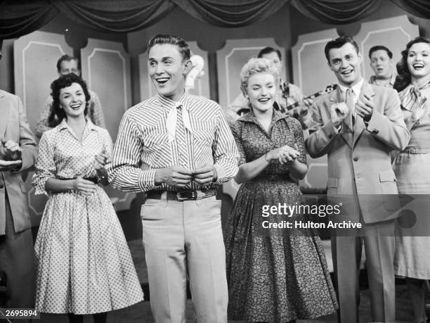 Singers Mary Klick, Jimmy Dean, J. Davis and Jan Crockel perform in front of musicians on a stage, possibly in a still from the television series,...