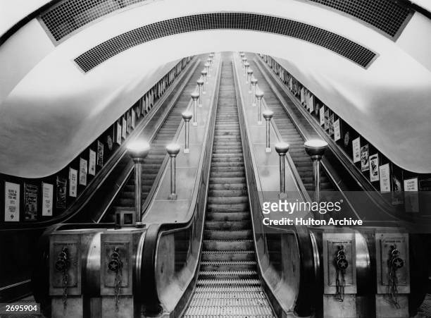 View from the bottom of the escalators at Leicester Square tube station on the Northern and Piccadilly lines, London, England. The escalators have a...