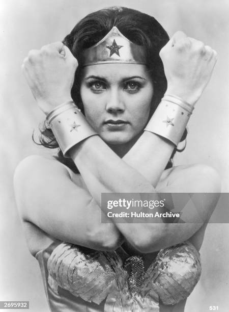 American actor Lynda Carter crosses her arms in front of her face in a promotional portrait for the television series, 'Wonder Woman'. She wears a...