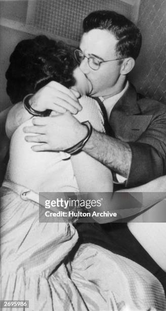 Married American traitors Julius and Ethel Rosenberg, wearing handcuffs, kiss in the back of a prison van after their treason arraignment, New York...