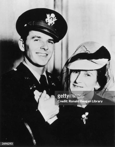 Portrait of American actor Ronald Reagan smiling and holding his mother Nelle's hand. He wears his US Army uniform and cap.