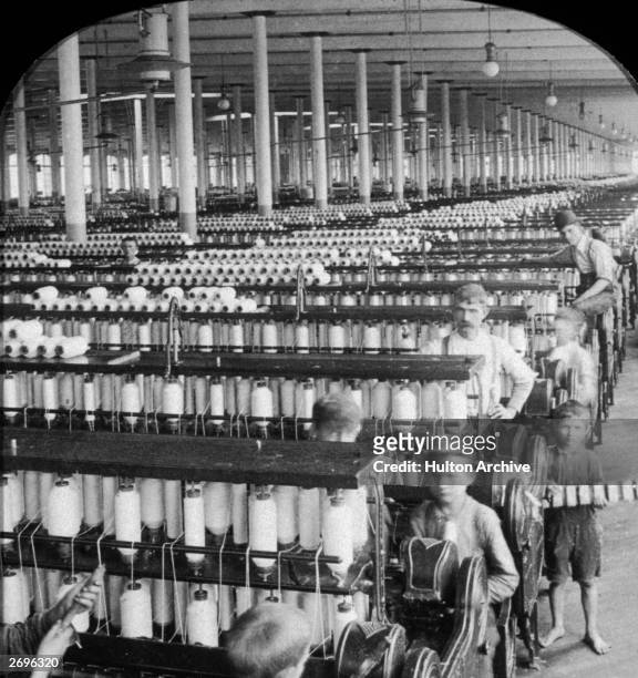 Boys and men work within huge rows of spinning machines in the spinning room of the Olympian Cotton Mills, Columbia, South Carolina.