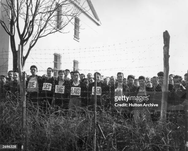 Pavlos Hellas political prisoners lined up behind barbed wire with 'The British Must Go' spelled out in French on their shirts, Greek Civil War,...