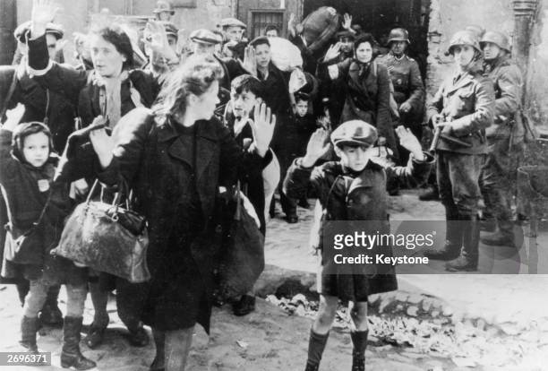 Group of Jewish civilians being held at gunpoint by German SS troops after being forced out of a bunker where they were sheltering during the Warsaw...