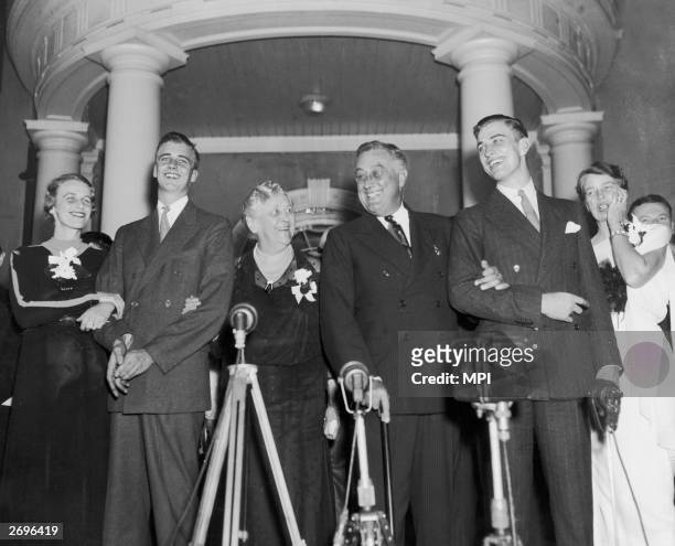 American president Franklin D. Roosevelt smiles as he st5ands with members of his family behind a bank of microphones at the entrance to his family...