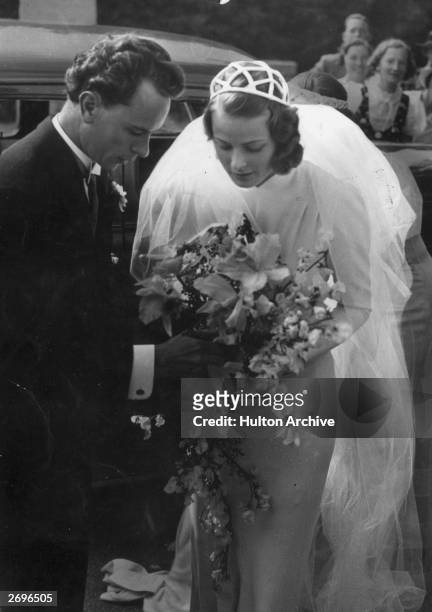Swedish-born actor Ingrid Bergman with her first husband, dentist Dr. Petter Lindstrom, at their wedding. They hold the bridal bouquet together.