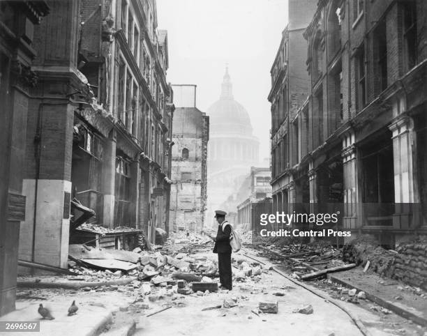 Postman tries to deliver letters to premises in Watling Street in the City of London, after a night time German air raid, London, May 1941. The dome...