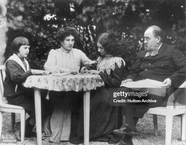 French novelist Emile Zola reading L'Aurore' newspaper at home with his family in Verneuil-sur-Seine. Left to right : Jacques, Zola's wife Jeanne,...