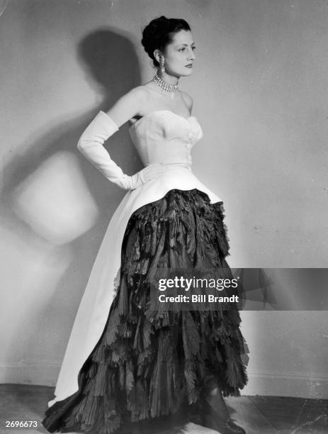 An evening dress designed by Cristobal Balenciaga with crisp white cotton pique cut away at the front to show a full skirt of soft black silk...