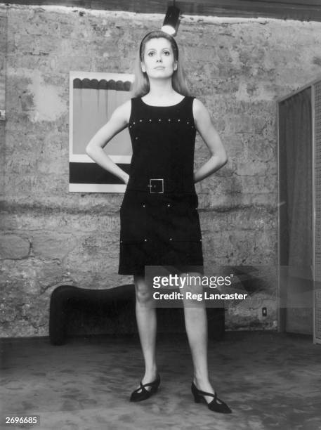 Catherine Deneuve modelling a 'small black dress' from ' Rive Gauche', Yves Saint Laurent's ready-to-wear boutique collection. The dress has no...