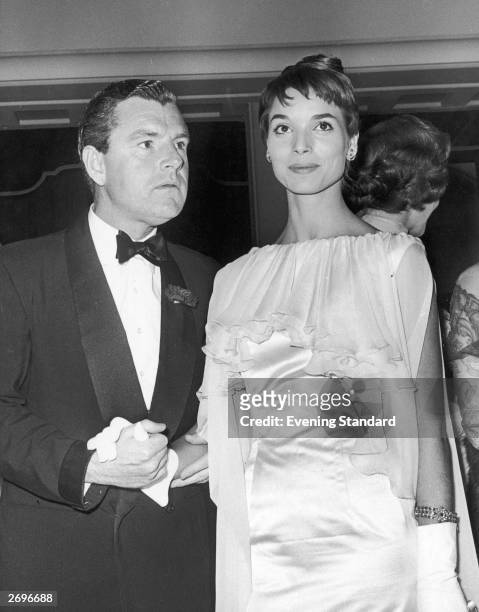 At the Odeon Cinema, Marble Arch, London, film star Kenneth Moore holds hands with Italian actress Elsa Martinelli who is wearing an evening dress...