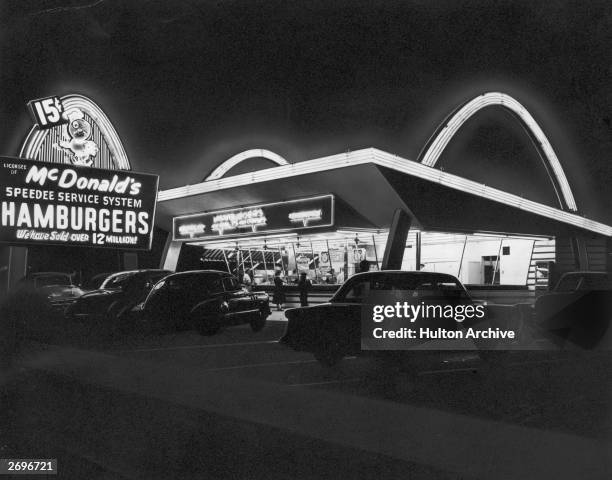 Exterior view of the first McDonald's fast food restaurant with its neon arches illuminated at night, Des Plaines, Illinois.