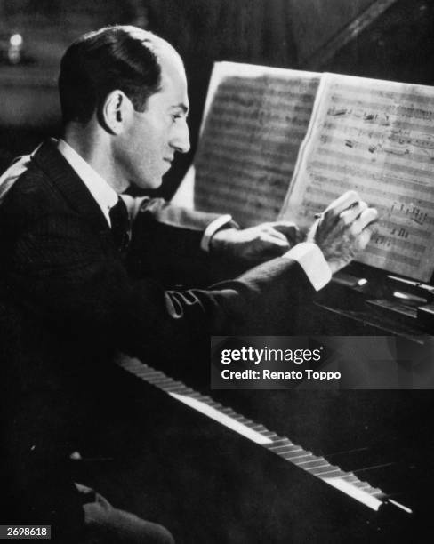 American composer George Gershwin sitting at a piano making an alteration to the score for 'Porgy and Bess'.