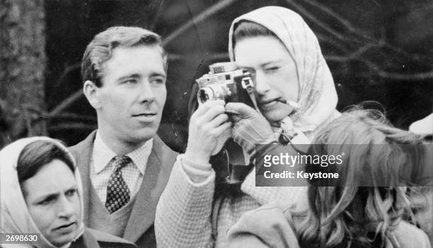 Professional photographer Antony Armstrong-Jones, the Earl of Snowdon, watches critically as his fiancee Princess Margaret takes a snap at the...