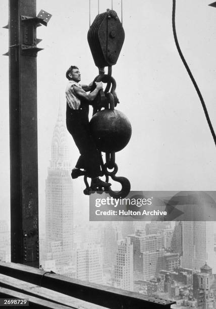 Construction worker stands on crane pulley counterweight during the construction of the Empire State Building, New York, New York. Mid to late 1930....