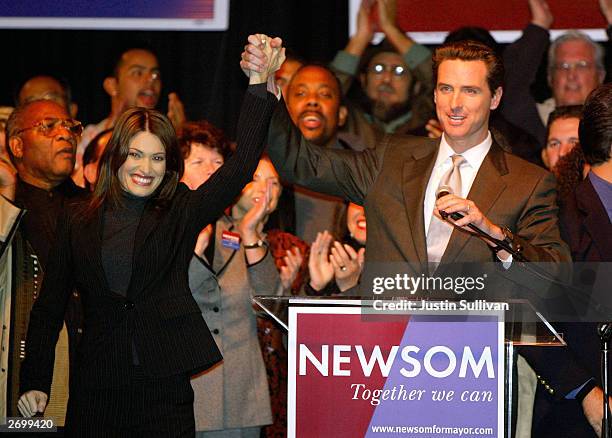 San Francisco mayoral candidate Gavin Newsom lifts arms with his wife Kimberly Guilfoyle Newsom before speaking to supporters at an election night...