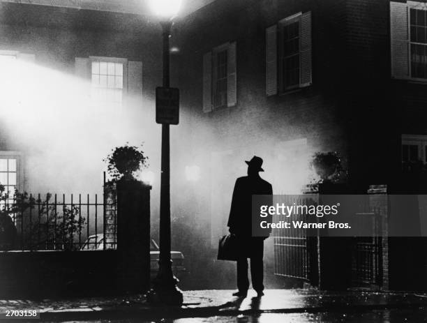 Silhouette of a man stands in front of a house at night in a still from the film,' The Exorcist', directed by William Friedkin, 1973.