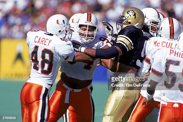 Defensive end Dwayne Johnson of the University of Miami Hurricanes helps a teammate with a block during the NCAA game against University of Colorado...