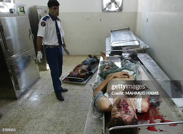 Palestinian medical worker stands over the bodies of two Palestinians in the morgue of Gaza City's al-Shifa hospital 08 November 2003. The two men...