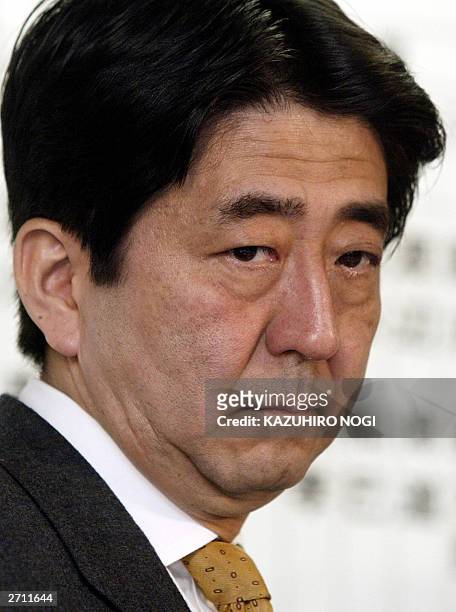 Shinzo Abe, secretary general of the Liberal Democratic Party , looks at a TV monitor reporting a vote counting in the general election for the House...