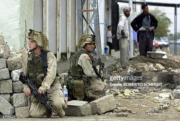 Two US soldiers from Charlie Company, 1-22, 4ID lay low as they briefly pause during a dismounted patrol in the streets of downtown Tikrit, north of...