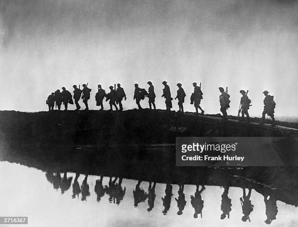 Supporting troops of the 1st Australian Division walking on a duckboard track near Hooge, in the Ypres Sector. They form a silhouette against the sky...