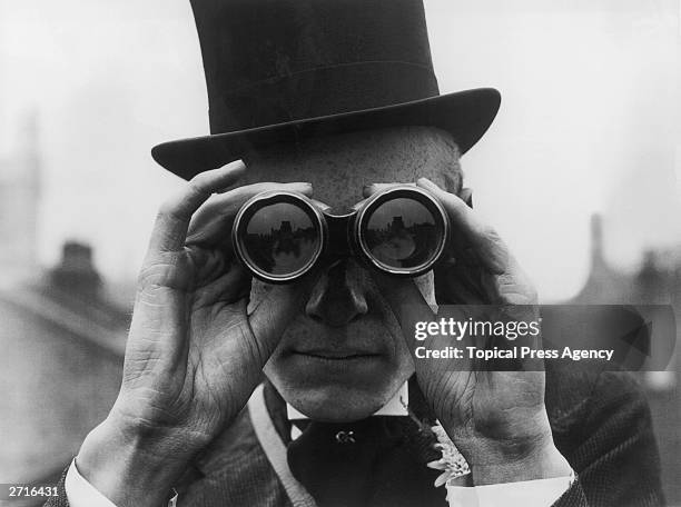 Spectator looking through binoculars at the Derby horse races, Epsom, Surrey, June 1923.