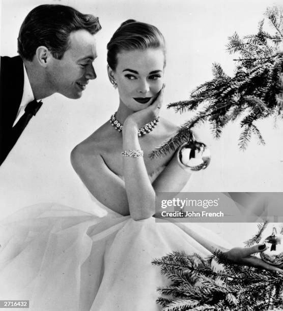 Couple flirting beside a Christmas tree, December 1955. The female model is Susan Abraham. Original Publication: Housewife Magazine - pub. 1955
