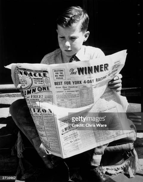 British jockey Lester Piggott, aged 12, reading his favourite newspaper 'The Winner' which gives him all the racing news. He is at his father's...