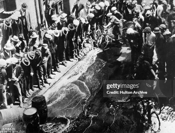 Contraband beer being spilled into the streets from barrels during the prohibition era.