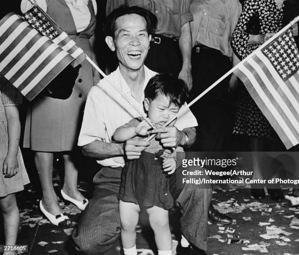 Father and son waving American flags at a parade in Chinatown, New York.