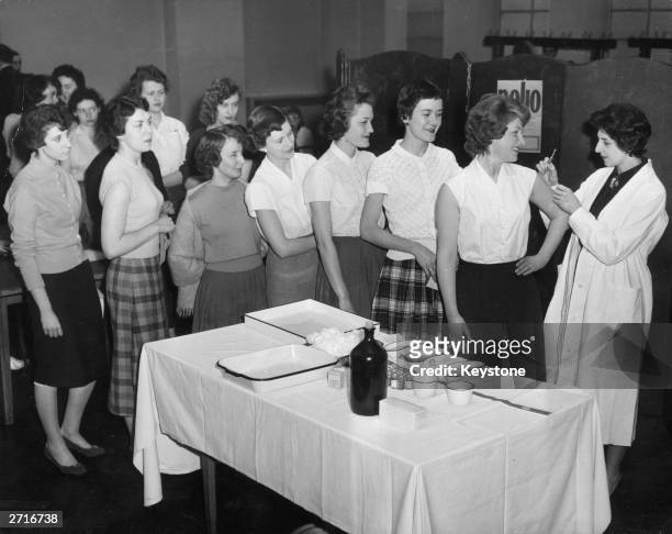 Junior members of staff at the Ministry of Health on Saville Row, London line up to receive their inoculation against polio, as part of a national...