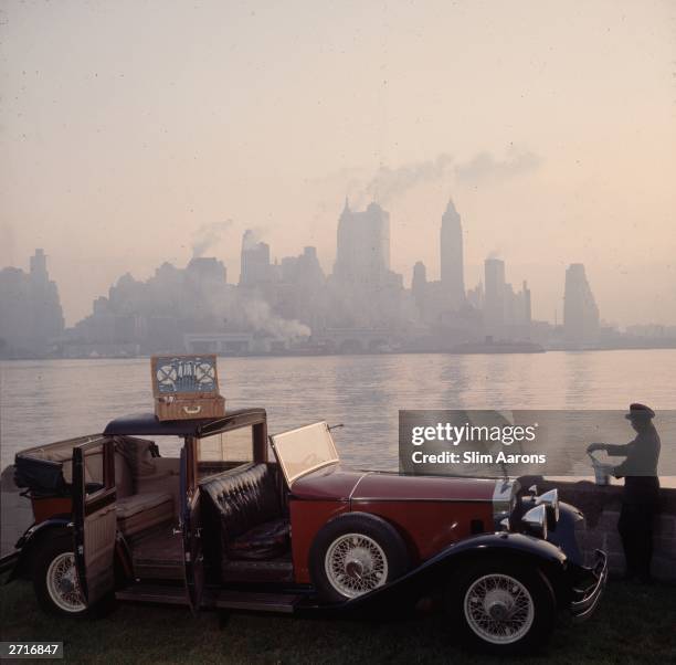 Premium Rates Apply. A chauffeur unpacks a picnic hamper from a Rolls Royce, against the New York skyline.