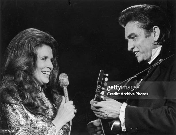 Married country singers Johnny Cash and June Carter Cash perform a duet on stage.