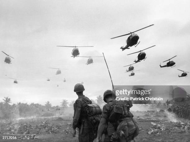The second wave of combat helicopters of the 1st Air Cavalry Division fly over an RTO and his commander on an isolated landing zone during Operation...