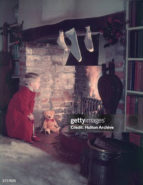 Young boy looking for Father Christmas up the chimney.