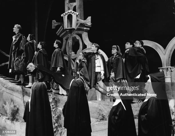 American actor Mary Martin leads a group of children and actor Theodor Bikel up a slope as nuns look on in the scene where the von Trapp family flees...