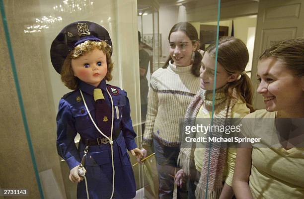 Group of girls look at a uniformed doll depicting a member of the Girl Guides of Canada given to Caroline Kennedy by the Girl Guides during...