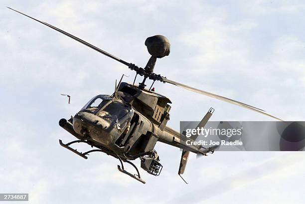 Army helicopter flies above as a crane is used to remove the wreckage of one of the U.S. Army Black Hawk helicopters on November 16, 2003 after it...