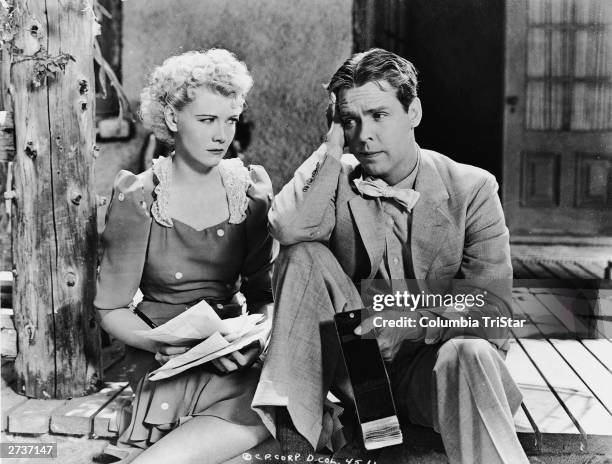 American actor Penny Singleton holds a bunch of papers and gives actor Arthur Lake a dirty look as he sits dejectedly on a porch holding an empty...